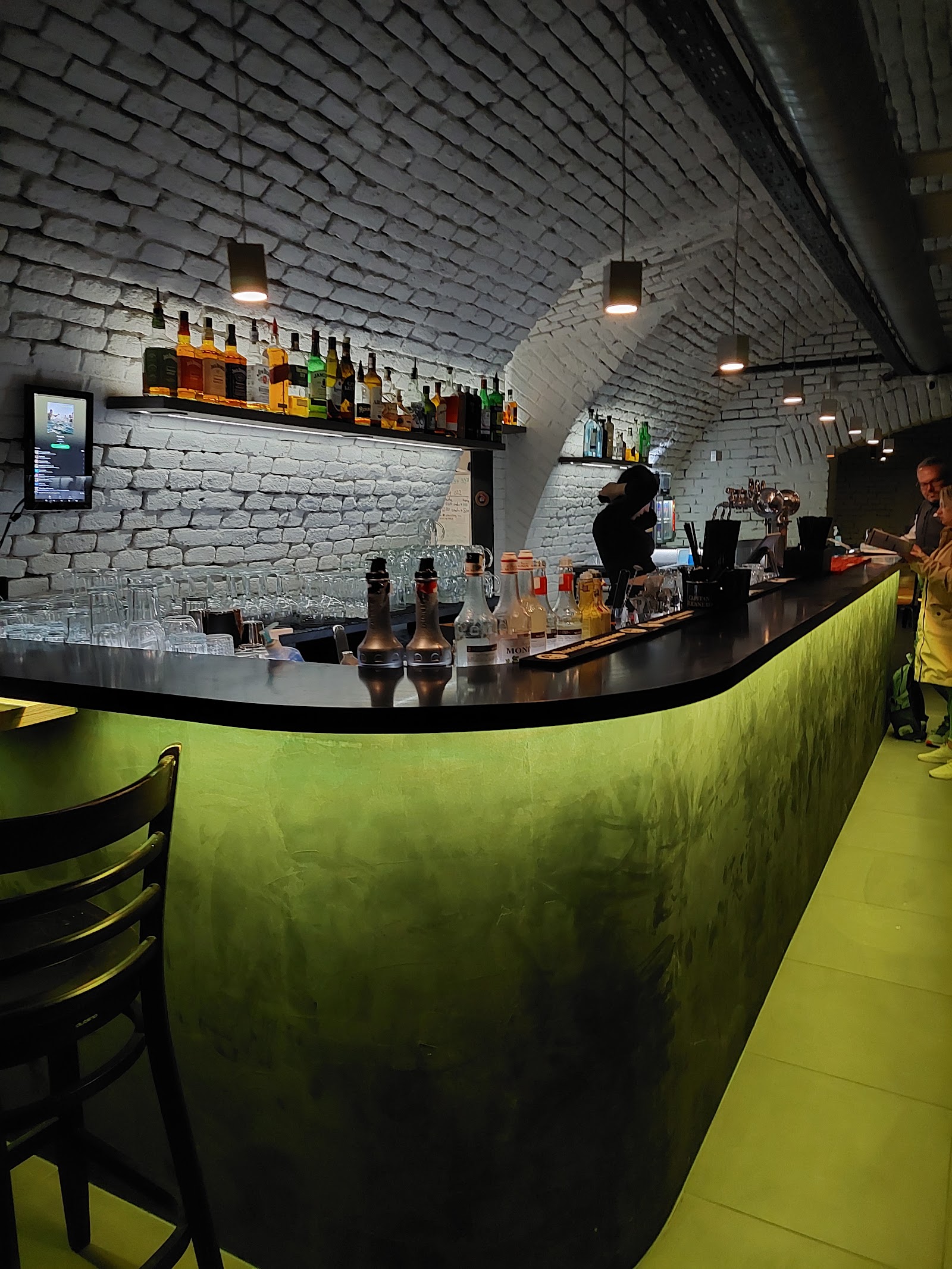 Zeleně podsvícený bar pult pod klenutým stropem